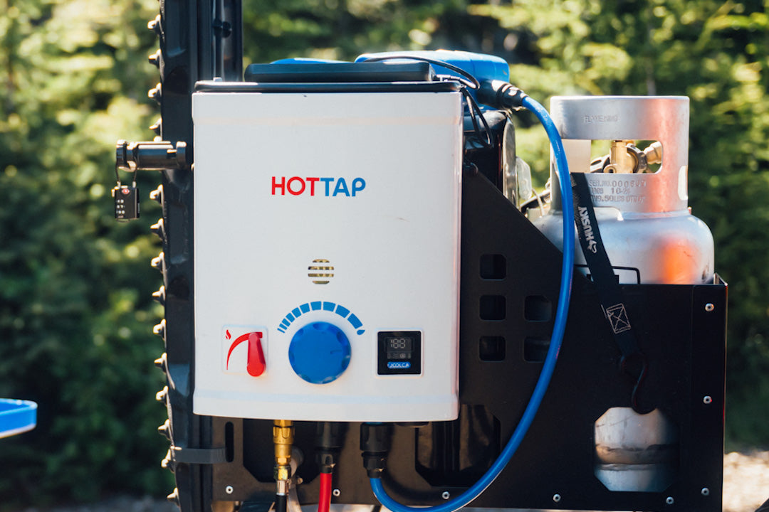 HOTTAP V2 mounted on a vehicle rack beside a gas bottle, with the blue shower hose attached