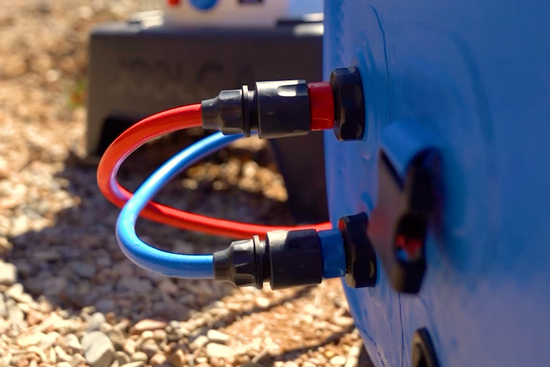 Close-up of red and blue hoses clipped into the quick-connect fittings on the side of a HOTTUB
