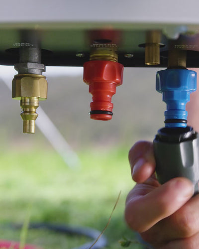 Close-up of a hand pushing the water hose onto the colour-coded quick-connect fittings under the HOTTAP V2.