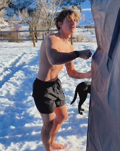 Man rinsing hot water through his hair inside a shower tent using the HOTTAP V2.
